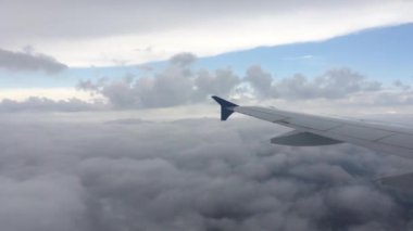 Uçak uçuşu. Bulutların üzerinde uçan bir uçağın kanadı. Uçağın penceresinden görüntüle