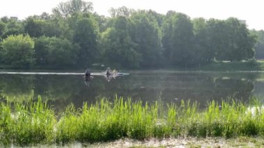 Moskova, Rusya, 11 Haziran 2020: İki genç adam yaz sabahının erken saatlerinde gölde iki kano üzerinde yüzüyor.