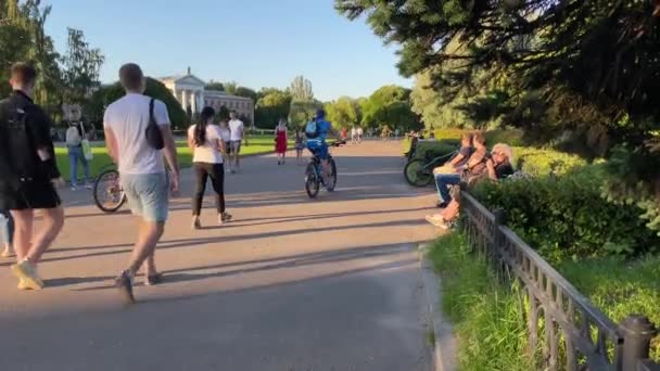 モスクワ ロシア 2020年6月24日 モスクワ科学アカデミー植物園 男性と女性は市内公園のアスファルトの道路に沿って歩いてください 人々は晴れた日に自転車に乗る — ストック動画