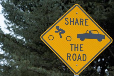 Yeşil ağaç ve arkasında mavi gökyüzü ile yol işareti paylaşmak