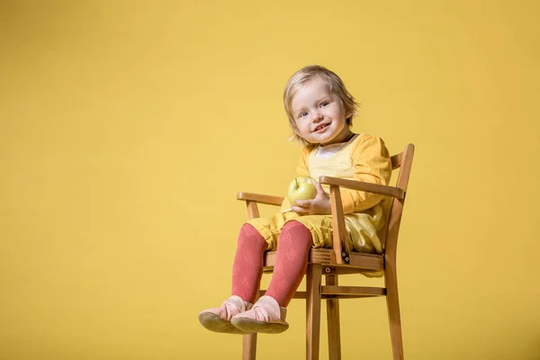 Junges Mädchen in gelbem Kleid auf gelbem Hintergrund Stockbild