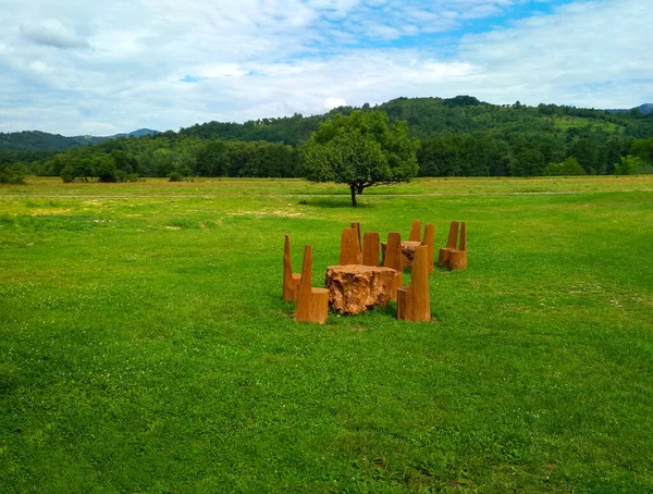 Table with solid wood chairs on a green lawn on a background of mountains, outdoor recreation