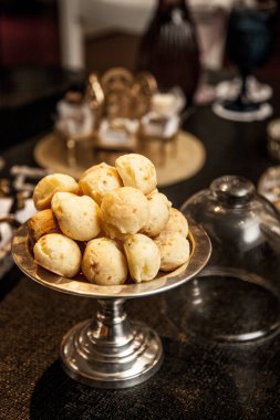 Brezilya, koyu ahşap masa, seçici odak üzerinde gümüş tepsi üzerinde peynir ekmek (pao de queijo) snack.