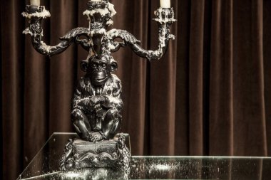 bir masaya gümüş mumluk mum yaktı. kahverengi zemin