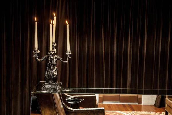 silver candle holder with candles lit on a table. brown background