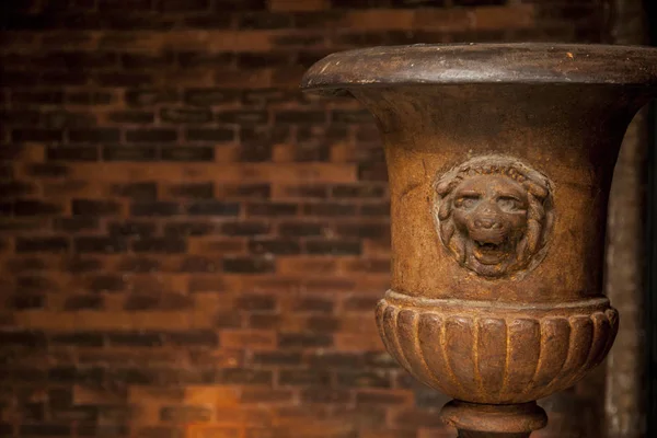 old lion flower vase in front of a brick wall