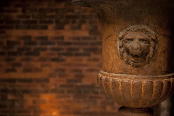 old lion flower vase in front of a brick wall