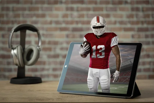 Football Player with a red uniform Playing playing and coming out of a tablet. Watching a football game on demand concept.