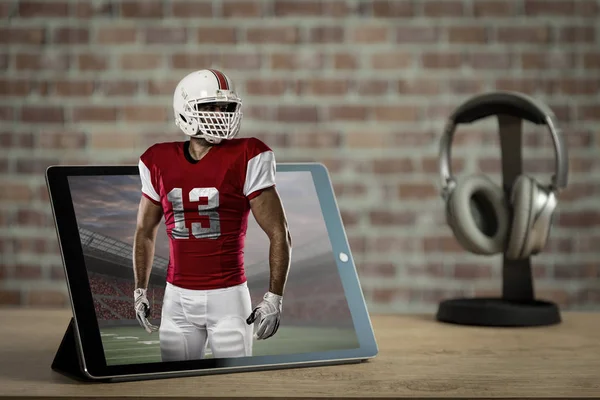 Football Player with a red uniform Playing playing and coming out of a tablet. Watching a football game on demand concept.