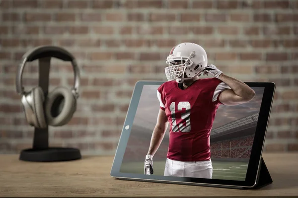 Football Player with a red uniform Playing playing and coming out of a tablet. Watching a football game on demand concept.
