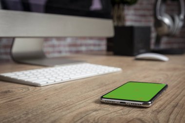 tam ekran Smartphone bir ofis önünde ahşap bir masa üstünde. Yeşil ekran için video, kopya alanı.