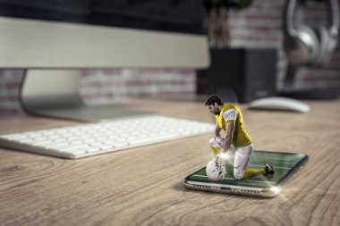 Oynama ve iyi bir tam ekran telefon ahşap bir masaya geliyor sarı üniforma ile futbolcu. Talep kavramı üzerinde bir futbol maçı izliyor. kopya alanı.