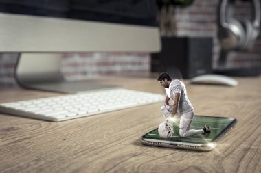 Oynama ve iyi bir tam ekran telefon ahşap bir masaya geliyor beyaz üniforma ile futbolcu. Talep kavramı üzerinde bir futbol maçı izliyor. kopya alanı.