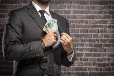 Brezilyalı adam para bir kelepçe ile faturalar bir hapiste tutan. yolsuzluk, yozlaşmış siyasetçiler, yasadışı işletmeler kavramı. tuğla arka plan.