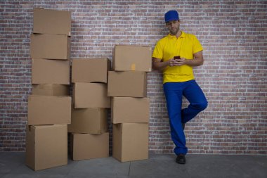 Brezilyalı postacı packag bir sürü önünde bir akıllı telefon kullanarak