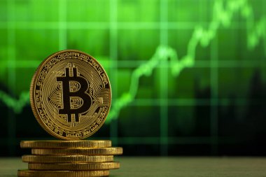 fiziksel bitcoin Yeşil grafik önünde ahşap bir masada duruyor. Bitcoin Bull Market konsepti.