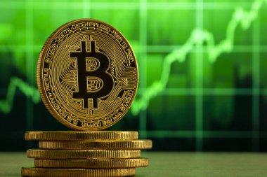 fiziksel bitcoin Yeşil grafik önünde ahşap bir masada duruyor. Bitcoin Bull Market konsepti.