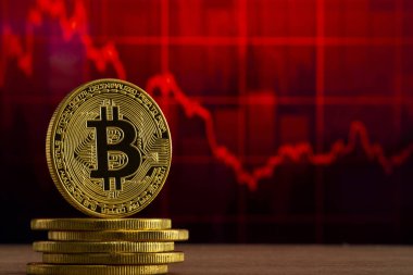 fiziksel bitcoin kırmızı bir grafik önünde ahşap bir masada duruyor. Bitcoin Bear Market konsepti
