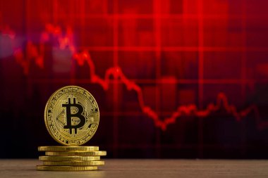 fiziksel bitcoin kırmızı bir grafik önünde ahşap bir masada duruyor. Bitcoin Bear Market konsepti