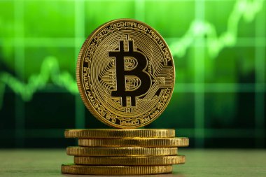 fiziksel bitcoin Yeşil grafik önünde ahşap bir masada duruyor. Bitcoin Bull Market konsepti.