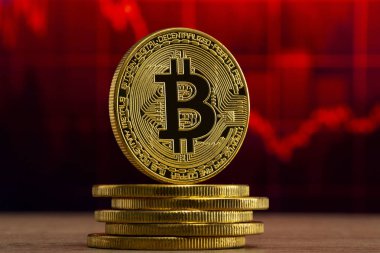 fiziksel bitcoin kırmızı bir grafik önünde ahşap bir masada duruyor. Bitcoin Bear Market konsepti