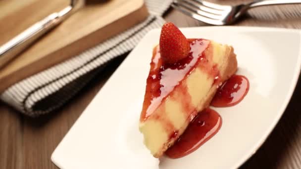 Deliciosa Fatia Cheesecake Morangos Uma Placa Branca Uma Mesa Madeira — Vídeo de Stock