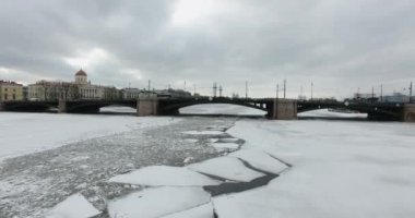 Havadan görünüm. Kışın bulutlu soğuk havalarda Neva nehri boyunca uçmak. Petersburg nehri üzerindeki köprü. Donmuş nehir üzerinde uçuş kuşların yüksekliği.