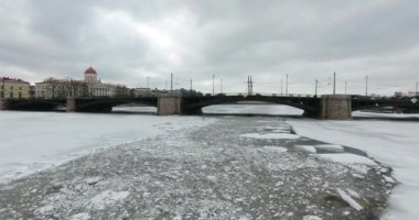 Havadan görünüm. Kışın bulutlu soğuk havalarda Neva nehri boyunca uçmak. Petersburg nehri üzerindeki köprü. Donmuş nehir üzerinde uçuş kuşların yüksekliği.