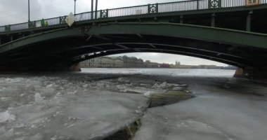 Havadan görünüm. Kışın bulutlu soğuk havalarda Neva nehri boyunca uçmak. Petersburg nehri üzerindeki köprü. Donmuş nehir üzerinde uçuş kuşların yüksekliği.