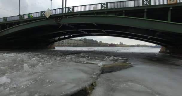 Widok z lotu ptaka. Latanie wzdłuż rzeki Neva w zimie pochmurny zimno. Most nad rzeką Petersburg. Wysokość lotu ptaków nad zamarzniętym rzeką. — Wideo stockowe