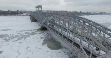 Havadan görünüm. Kışın bulutlu soğuk havalarda Neva nehri boyunca uçmak. Petersburg nehri üzerindeki köprü. Donmuş nehir üzerinde uçuş kuşların yüksekliği.