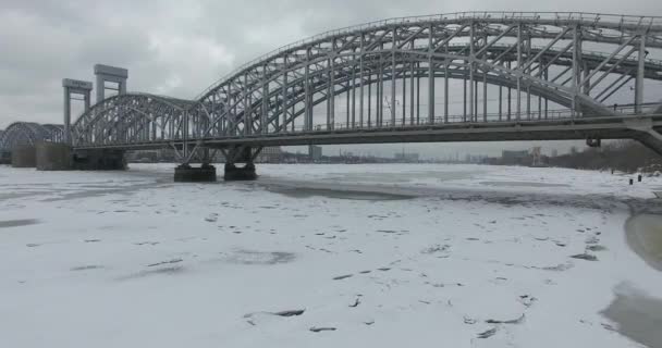 Luchtfoto. Vliegen langs de rivier de Neva in de winter overgegoten koud weer. Brug over de rivier de Petersburg. De hoogte van de vogelvlucht boven de bevroren rivier. — Stockvideo