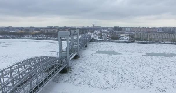 Havadan görünüm. Kışın bulutlu soğuk havalarda Neva nehri boyunca uçmak. Petersburg nehri üzerindeki köprü. Donmuş nehir üzerinde uçuş kuşların yüksekliği. — Stok video