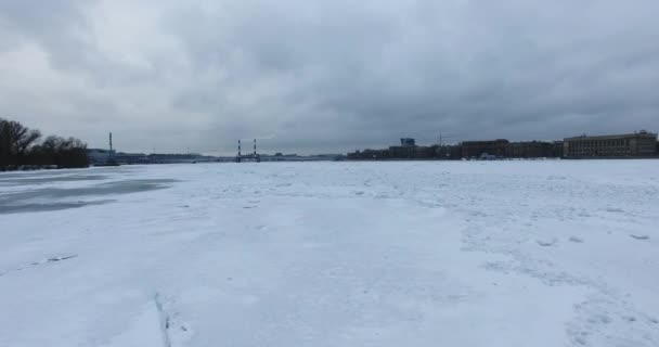 Vista aérea. Volando a lo largo del río Neva en invierno nublado clima frío. Puente sobre el río Petersburgo. La altura de las aves vuelan sobre el río congelado . — Vídeos de Stock
