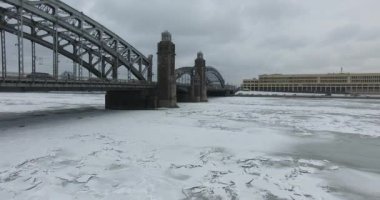 Havadan görünüm. Kışın bulutlu soğuk havalarda Neva nehri boyunca uçmak. Petersburg nehri üzerindeki köprü. Donmuş nehir üzerinde uçuş kuşların yüksekliği.