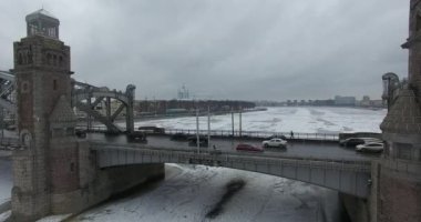 Havadan görünüm. Kışın bulutlu soğuk havalarda Neva nehri boyunca uçmak. Petersburg nehri üzerindeki köprü. Donmuş nehir üzerinde uçuş kuşların yüksekliği.