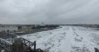 Havadan görünüm. Kışın bulutlu soğuk havalarda Neva nehri boyunca uçmak. Petersburg nehri üzerindeki köprü. Donmuş nehir üzerinde uçuş kuşların yüksekliği.