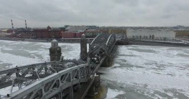 Havadan görünüm. Kışın bulutlu soğuk havalarda Neva nehri boyunca uçmak. Petersburg nehri üzerindeki köprü. Donmuş nehir üzerinde uçuş kuşların yüksekliği.