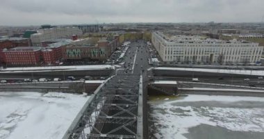 Havadan görünüm. Kışın bulutlu soğuk havalarda Neva nehri boyunca uçmak. Petersburg nehri üzerindeki köprü. Donmuş nehir üzerinde uçuş kuşların yüksekliği.