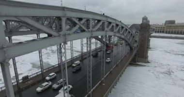 Havadan görünüm. Kışın bulutlu soğuk havalarda Neva nehri boyunca uçmak. Petersburg nehri üzerindeki köprü. Donmuş nehir üzerinde uçuş kuşların yüksekliği.
