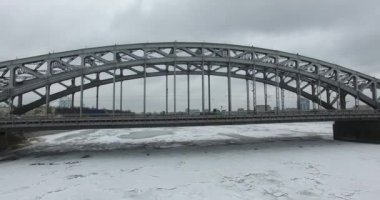 Havadan görünüm. Kışın bulutlu soğuk havalarda Neva nehri boyunca uçmak. Petersburg nehri üzerindeki köprü. Donmuş nehir üzerinde uçuş kuşların yüksekliği.