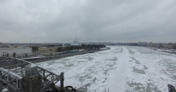 Widok z lotu ptaka. Latanie wzdłuż rzeki Neva w zimie pochmurny zimno. Most nad rzeką Petersburg. Wysokość lotu ptaków nad zamarzniętym rzeką. — Wideo stockowe