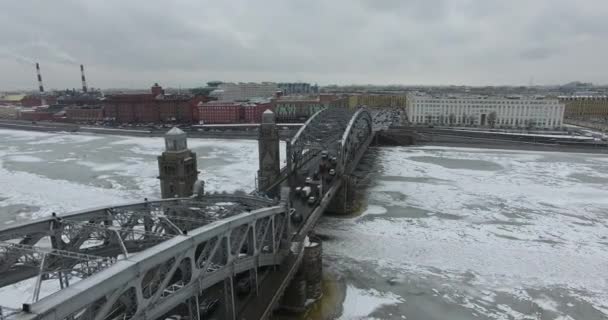 Вид з повітря. Пролетівши по річці Нева в зимовий час похмуре холодна погода. Міст через річку Петербург. Висота польоту птахів над замерзломою річкою. — стокове відео