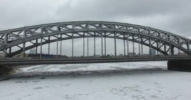 Luchtfoto. Vliegen langs de rivier de Neva in de winter overgegoten koud weer. Brug over de rivier de Petersburg. De hoogte van de vogelvlucht boven de bevroren rivier. — Stockvideo