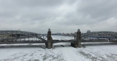Havadan görünüm. Kışın bulutlu soğuk havalarda Neva nehri boyunca uçmak. Petersburg nehri üzerindeki köprü. Donmuş nehir üzerinde uçuş kuşların yüksekliği.