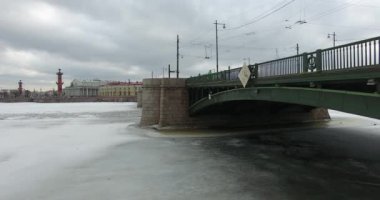 Havadan görünüm. Kışın bulutlu soğuk havalarda Neva nehri boyunca uçmak. Petersburg nehri üzerindeki köprü. Donmuş nehir üzerinde uçuş kuşların yüksekliği.