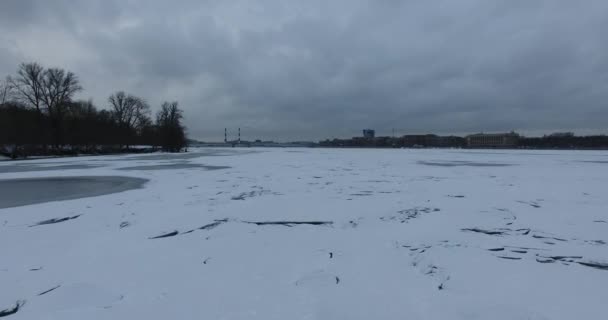 Havadan görünüm. Kışın bulutlu soğuk havalarda Neva nehri boyunca uçmak. Petersburg nehri üzerindeki köprü. Donmuş nehir üzerinde uçuş kuşların yüksekliği. — Stok video