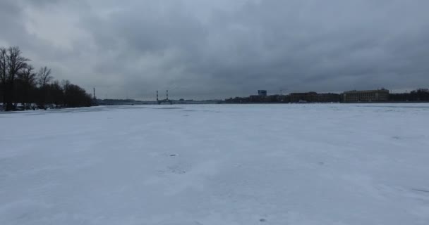 Vista aerea. Volare lungo il fiume Neva in inverno nuvoloso freddo. Ponte sul fiume Pietroburgo. L'altezza del volo degli uccelli sul fiume ghiacciato . — Video Stock