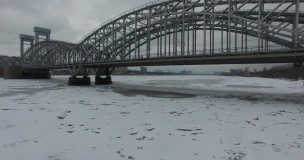 Luchtfoto. Vliegen langs de rivier de Neva in de winter overgegoten koud weer. Brug over de rivier de Petersburg. De hoogte van de vogelvlucht boven de bevroren rivier. — Stockvideo