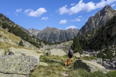 Aig estortes i Estany de Sant Maurici milli parkında köpek ve kadın yürüyüş.
